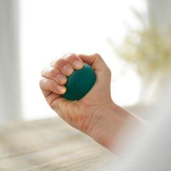 A close-up of a person squeezing the Sissel Press-Ball to improve grip strength, mobility, and dexterity as part of a hand rehabilitation routine.