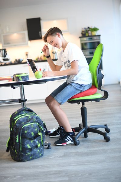 Young boy doing homework while sitting on the Sissel Sitfit Plus Balance Cushion to support posture and focus.