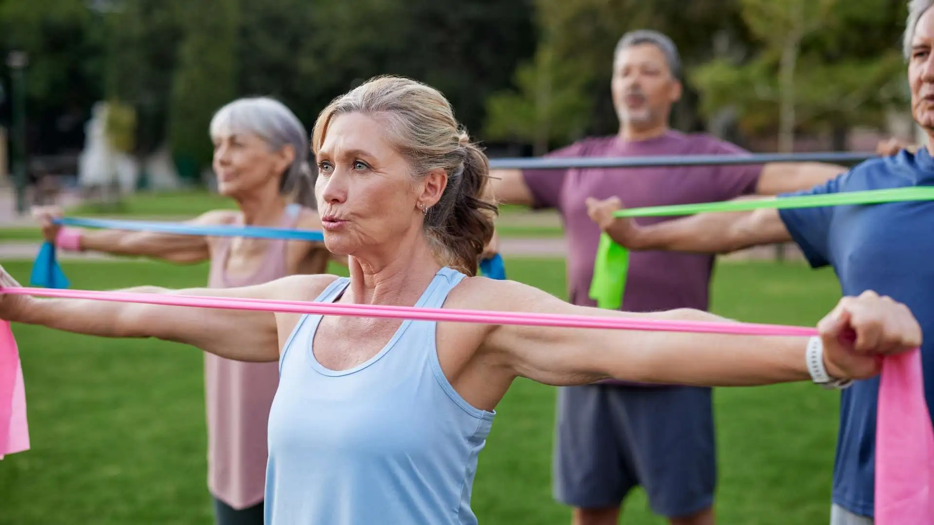 Group of elderly people working out in the park using resistance bands.