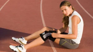 Young athlete resting on the ground after a long run. She is wearing knee support on her left leg.