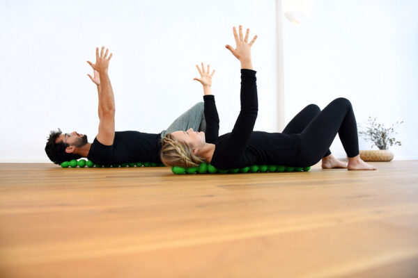 Man and woman lying side by side using the Sissel Spinefitter for spinal support
