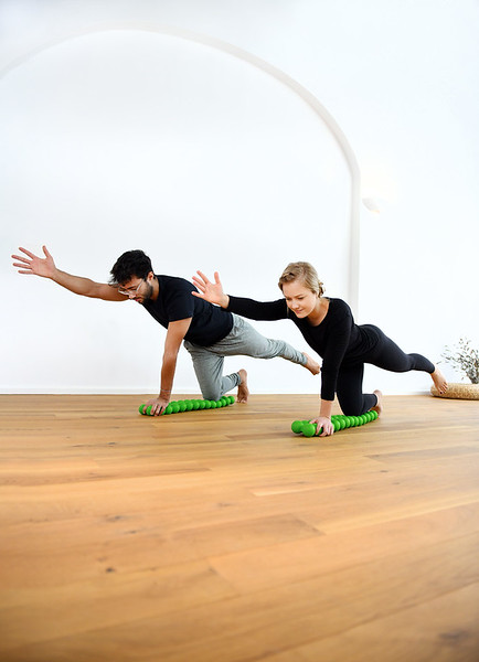 Man and woman balancing on their knees on the Sissel Spinefitter, raising arms for coordination training