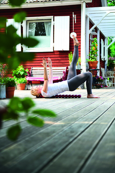 Woman lying on the Sissel Spinefitter, lifting her hips (bridge pose) for muscle activation