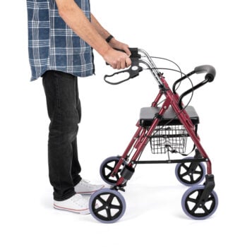 Person pushing the 4-wheeled rollator, demonstrating mobility support and stability.