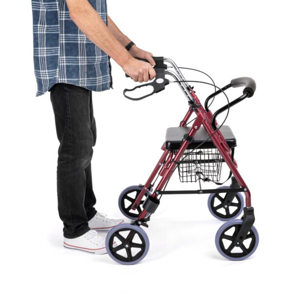Person pushing the 4-wheeled rollator, demonstrating mobility support and stability.
