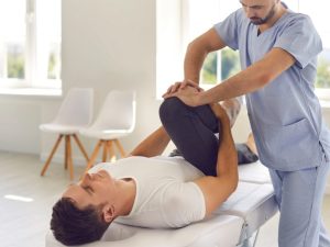A physiotherapist providing treatment to a patient on a physical therapy treatment table, demonstrating its use in sports rehabilitation and therapy.