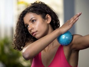 Person using a massage ball to relieve plantar fasciitis pain by rolling it under the foot to reduce tension and improve flexibility.