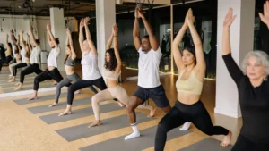 A yoga studio with over ten people practicing yoga on their yoga mats, following an instructor.
