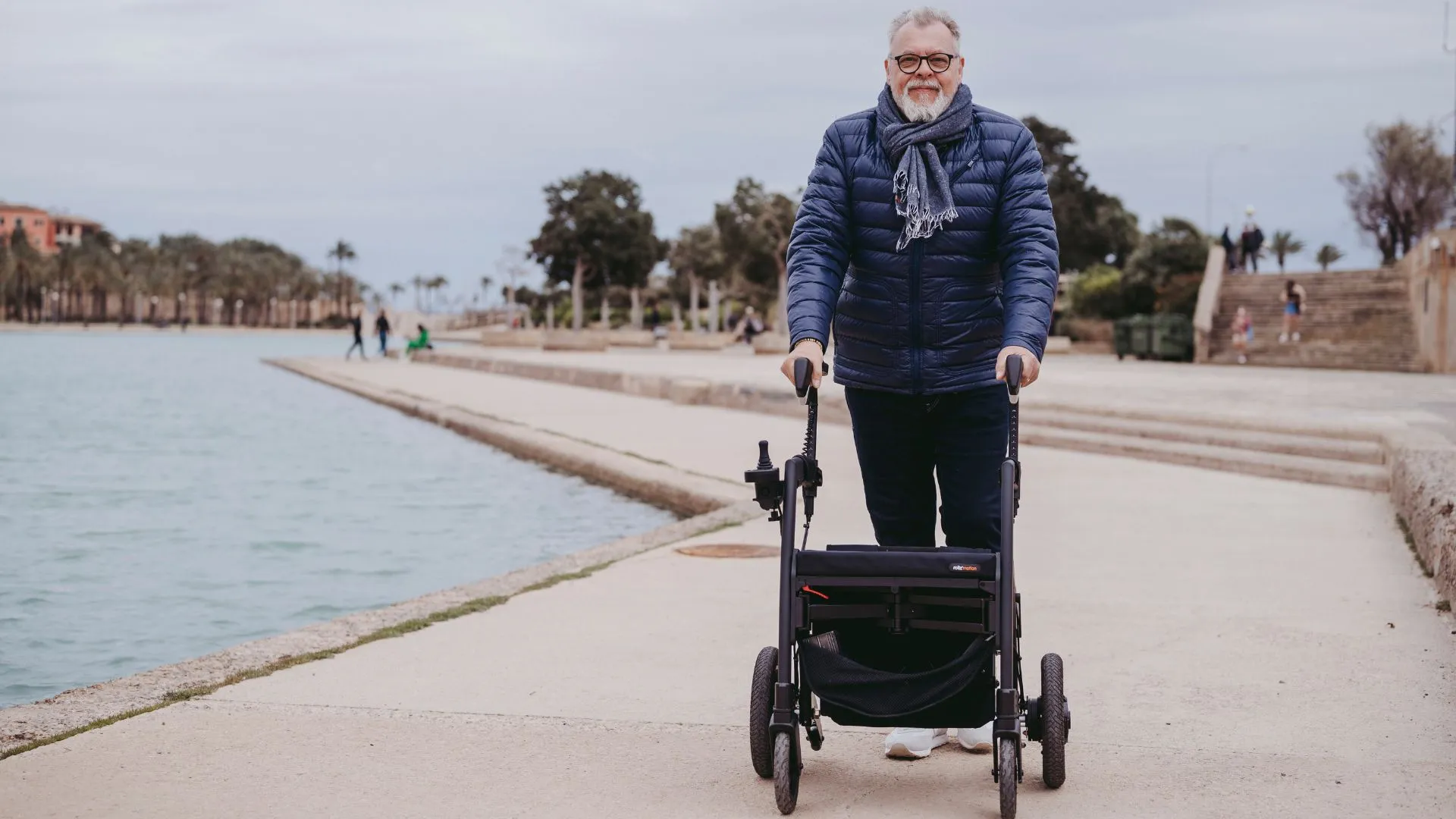 Man walking on the seaside with an outdoor rollator walker.