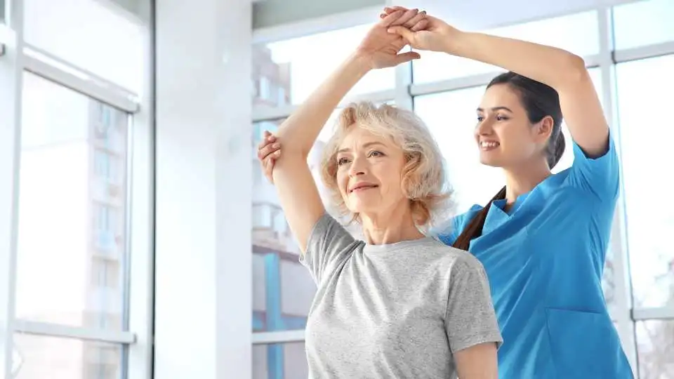Physio checking an elderly woman's joint movement.