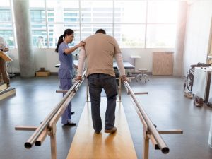 Physical therapist assisting a patient in parallel bar training to improve balance and stability in a rehabilitation setting