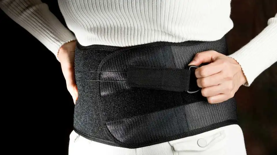 A female wearing back support belt and preparing for a light workout to help her aid her recovery.