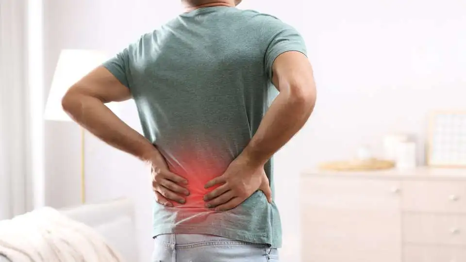 A young man holding his lower back as he is in pain and need a back support belt.