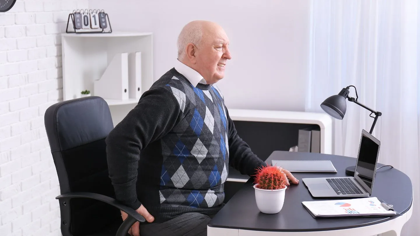Man experiencing hemorrhoid pain on the office chair while at work.