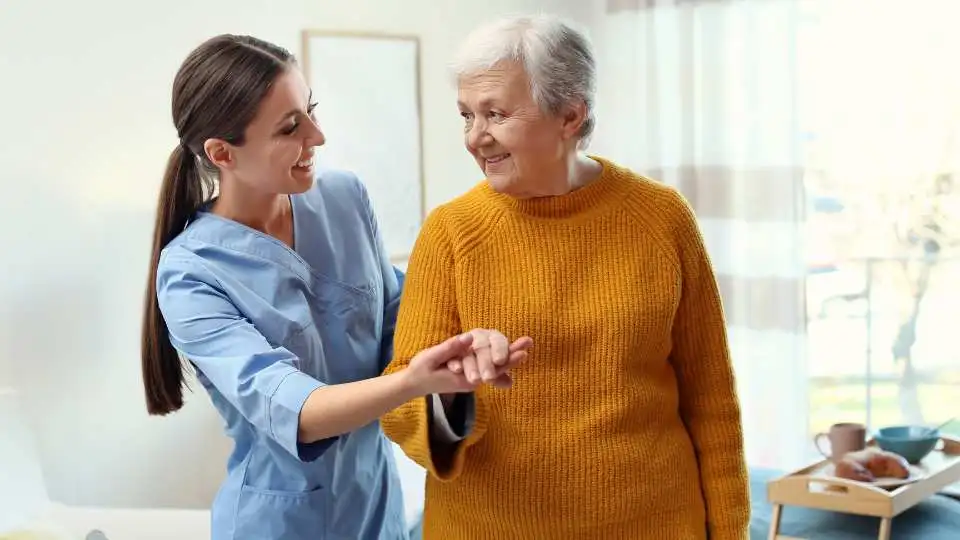 A carer helping a stroke patient to get off the bed after breakfast.