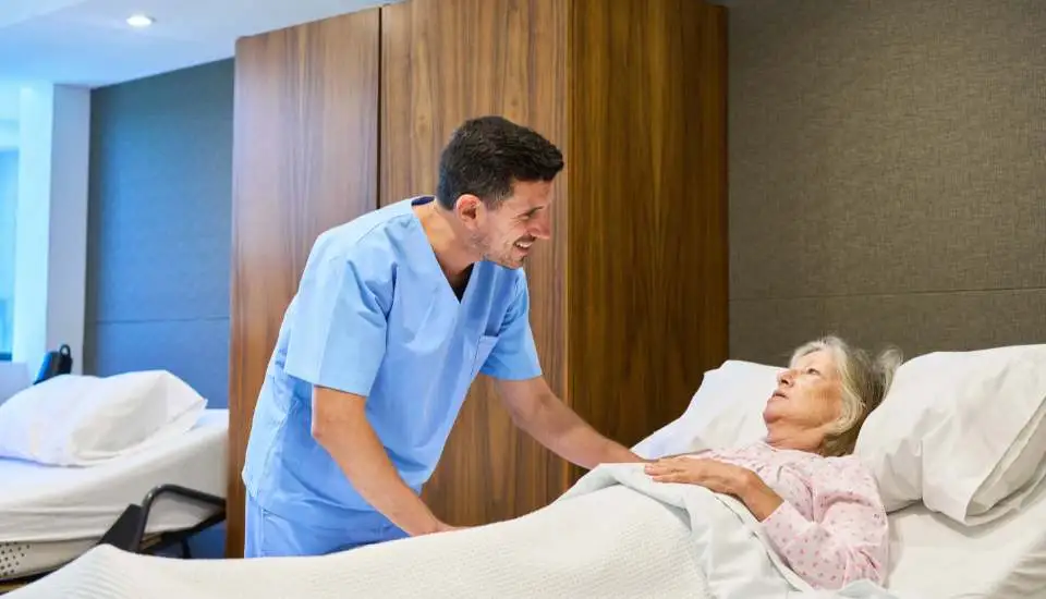 AN incontinent elderly woman preparing to go to sleep and a care worker is friendly and smiling at her.