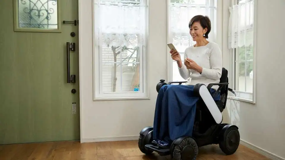 A woman using a wheelchair that has additional features like cup holder and storage bag.