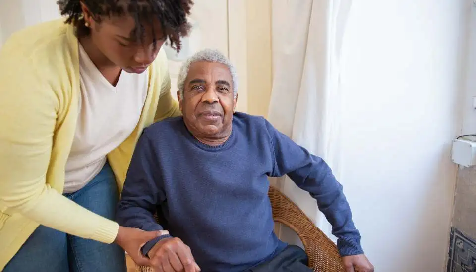 Young woman helps an elderly person get up from the chair to go to the toilet.