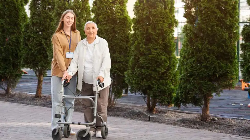 Elderly lady using a forearm rollator outdoors.