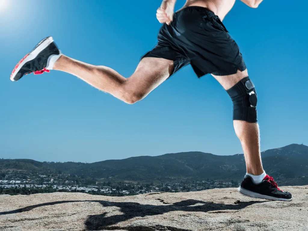 Young man running with a knee brace on his right leg.