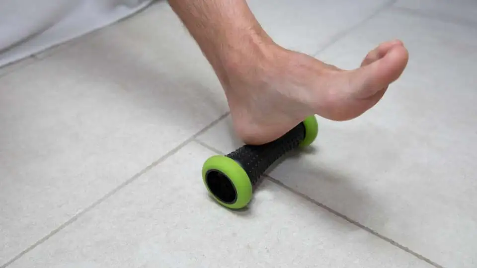 Man rolling his foot arch on a foot roller.