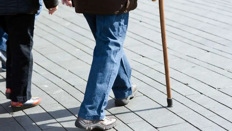 Man walking with a wooden walking stick outdoors .
