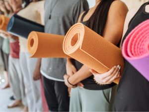 Group of people holding colorful yoga and pilates mats, highlighting their differences and uses for various exercise practices