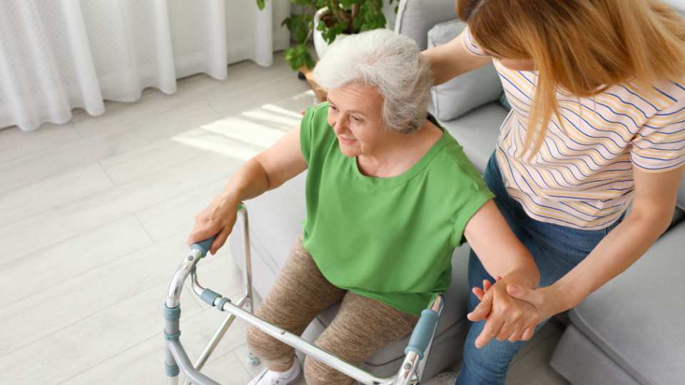Elderly lady learning how to use a zimmer frame after using a wlaking stick for a long time.