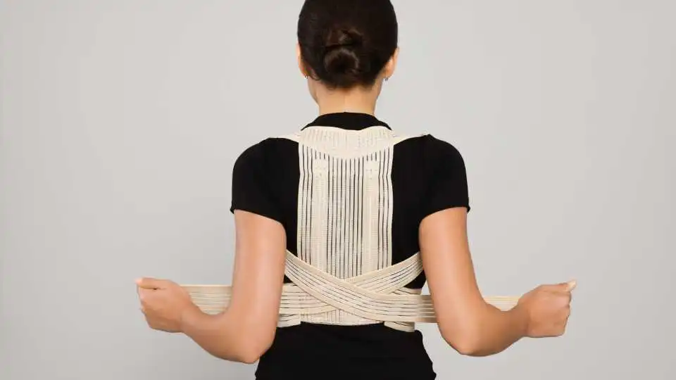 Young woman using a back brace with adjustable straps to help her release tension while sleeping.