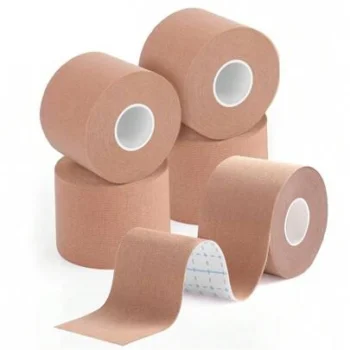 Five rolls of beige kinesiology tape stacked and arranged, with one strip partially unrolled to show the adhesive side.