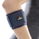 Person wearing a neoprene epicondylitis brace on forearm for tennis or golfer’s elbow support