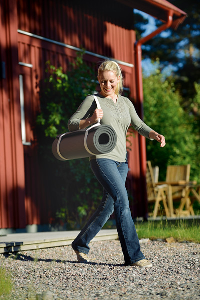 Woman using the SISSEL Yoga and Pilates Mat Carry Strap to carry a rolled-up yoga mat over her shoulder